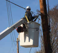 Utility worker in bucket working near power lines