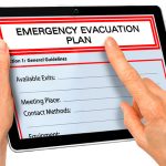 Close up of hands touching tablet with emergency evacuation plan document
