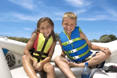 Young girl and boy smiling on boat wearing life jackets